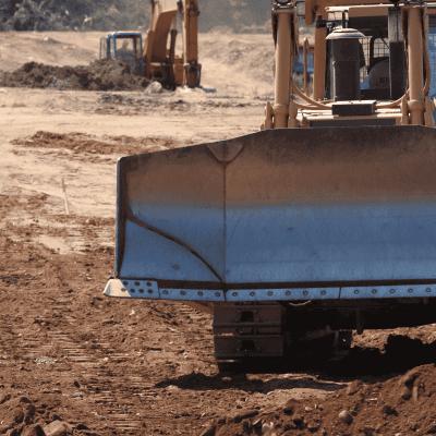 AT and Komatsu bulldozers with U dozer blades pushing earth on a road construction site